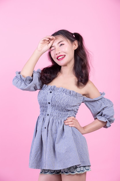 Fashion girl dress up with hand gestures on a pink background.