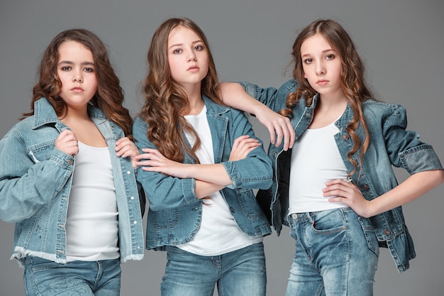 fashion girls standing together and looking at camera over gray studio