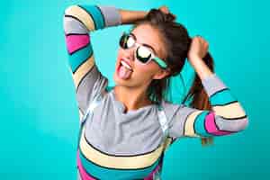 Free photo fashion lifestyle portrait of joyful funny woman, sexy full lips, mirrored sunglasses, holding her hairs like two ponytails, spring colors, mint background. cute emotions, trendy woman.