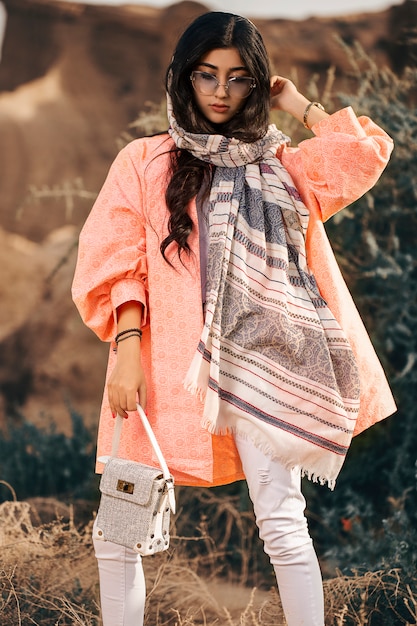 Free photo fashion model in coral jacket and black shawl with white pants