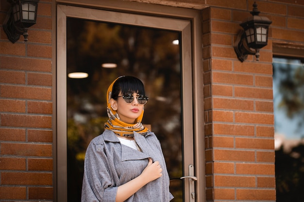 선글라스와 회색 재킷과 오렌지 숄의 패션 모델