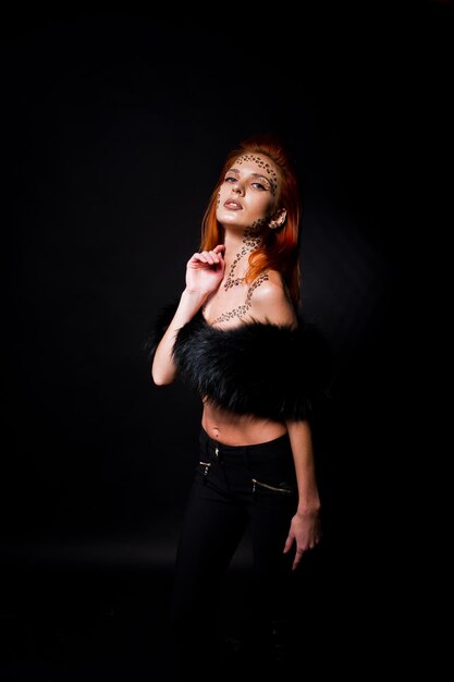 Fashion model red haired girl with originally make up like leopard predator isolated on black Studio portrait