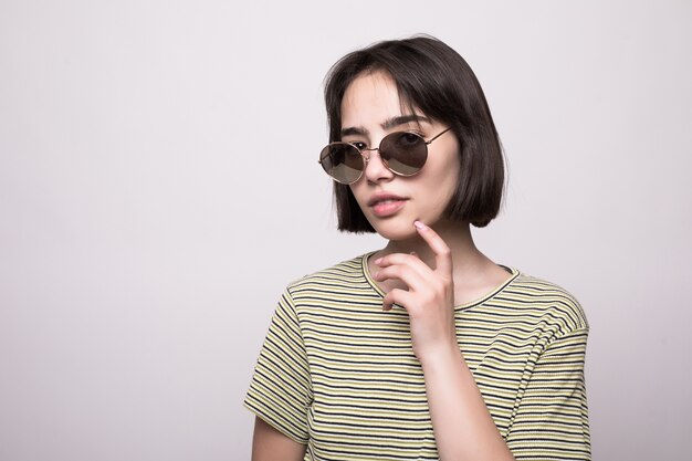 Fashion model with short hair. Young girl in sunglasses with hands near face posing