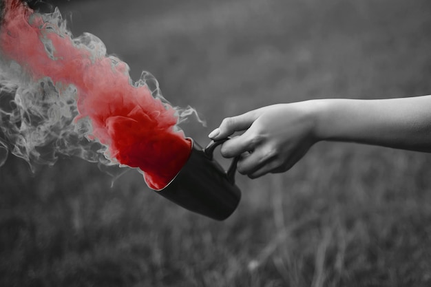 Foto di moda di mano con tazza e fumo rosso