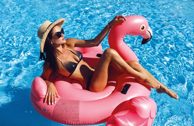 fashion photo of sexy beautiful girl in black bikini relaxing beside a swimming pool,