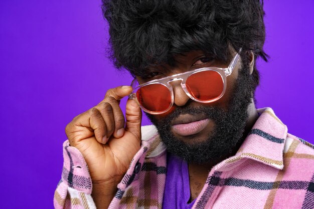 Модный портрет афро-американского мужчины в очках на фиолетовом фоне