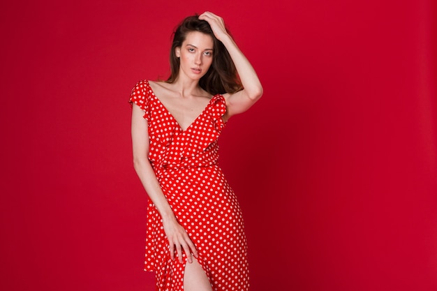 레드 스튜디오에 빨간색 점선 드레스에 매력적인 웃는 젊은 여자의 패션 초상화