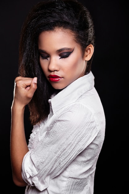 fashion portrait of beautiful american black female brunette girl model with bright makeup red lips in white shirt. 