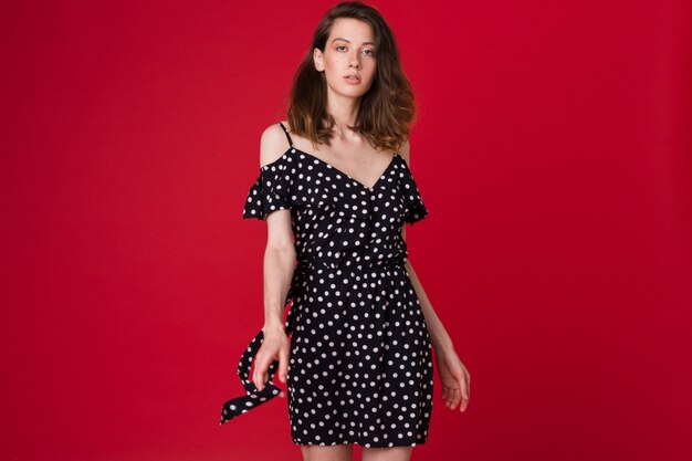빨간 스튜디오에 검은 점선 드레스에서 아름 다운 젊은 여자의 패션 초상화