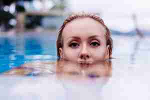 Free photo fashion portrait of caucasian woman in bikini in blue swimming pool on vacation at coudy day natural light