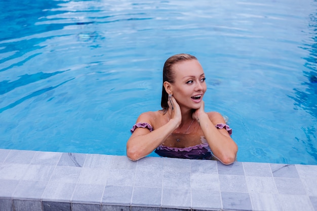 Foto gratuita adatti il ritratto della donna caucasica in bikini nella piscina blu in vacanza alla luce naturale del giorno coudy