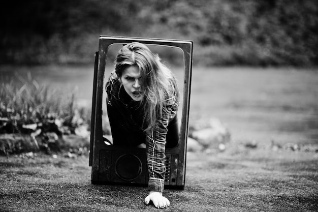 Fashion portrait of redhaired sexy girl outdoor model attractive dramatic woman with old tv box