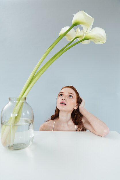 Fashion portrait of a redheaded woman sitting at the table