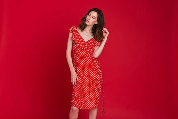 Fashion portrait of smiling young woman in red dotted dress on red