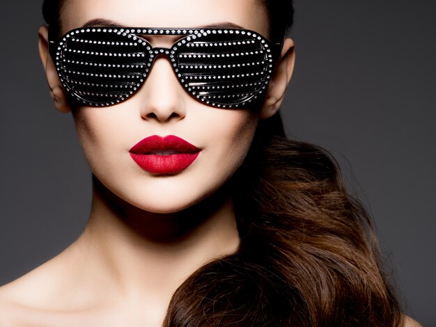 다이아몬드와 붉은 입술과 검은 선글라스를 착용하는 여자의 패션 초상화