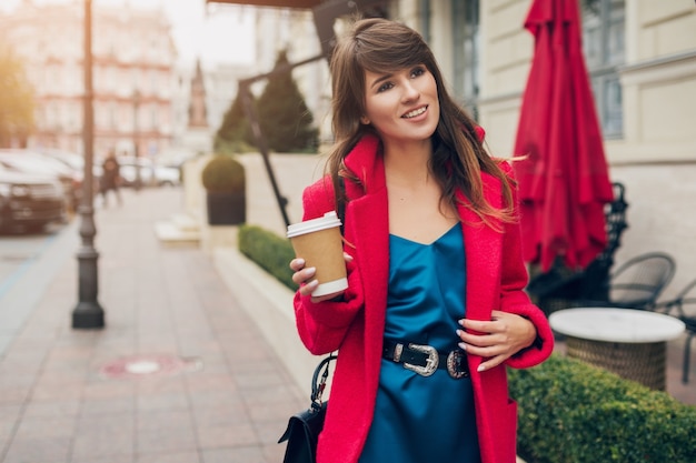 빨간 코트, 가을 스타일 트렌드, 커피를 마시고, 웃고, 행복하고, 파란색 실크 드레스를 입고 도시 거리에서 걷는 젊은 아름 다운 세련 된 여자의 패션 초상화
