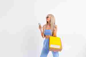 Free photo fashion portrait of young blonde woman with long gorgeous straight hair hold colorful shopping bags