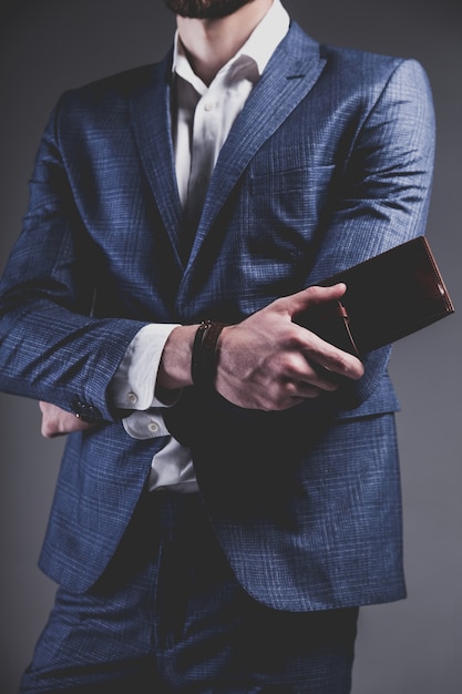 Free photo fashion portrait of young businessman handsome model man dressed in elegant blue suit on gray