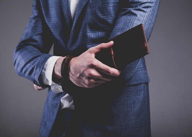 Fashion portrait of young businessman handsome model man dressed in elegant blue suit on gray