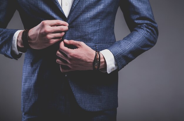 Fashion portrait of young businessman handsome model man dressed in elegant blue suit on gray