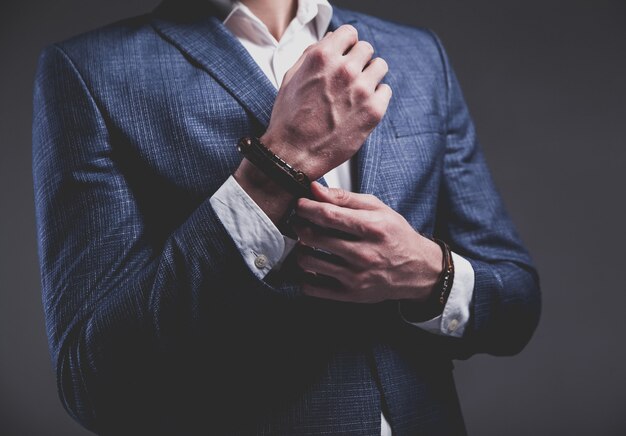 Fashion portrait of young businessman handsome model man dressed in elegant blue suit on gray