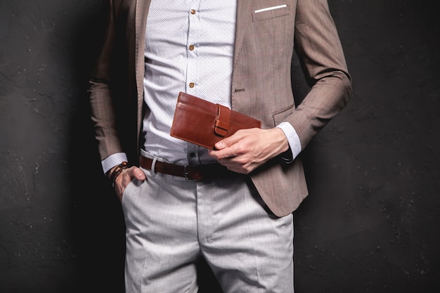 アクセサリーとエレガントな茶色のスーツに身を包んだ青年実業家ハンサムなモデル男のファッションポートレート