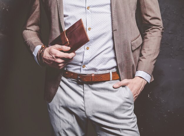 Fashion portrait of young businessman handsome model man dressed in elegant brown suit with accessories