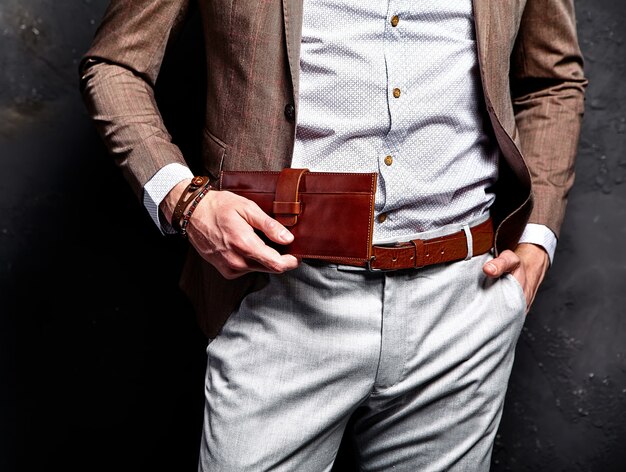 Fashion portrait of young businessman handsome model man dressed in elegant brown suit with accessories