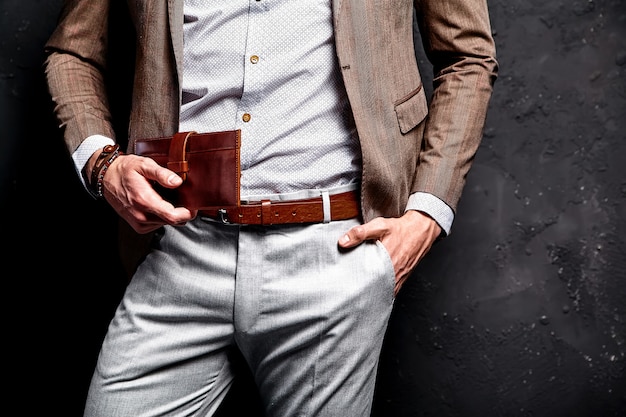 Fashion portrait of young businessman handsome model man dressed in elegant brown suit with accessories