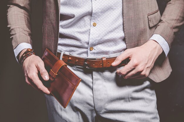 Fashion portrait of young businessman handsome model man dressed in elegant brown suit with accessories