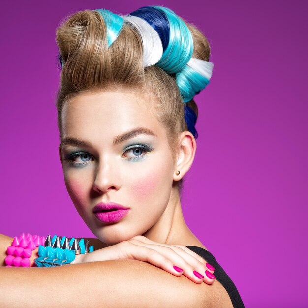 Fashion portrait of young caucasian model with bright makeup Beautiful woman with creative hairstyle woman with   Portrait of a girl with bracelets on her hands