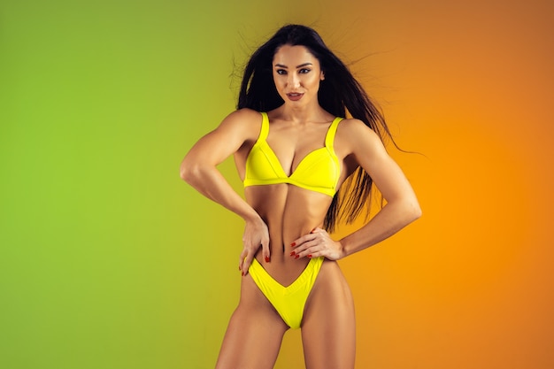 Fashion portrait of young fit and sportive woman in stylish yellow luxury swimwear. Perfect body ready for summertime.