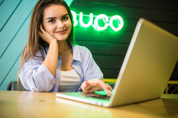 Fashion portrait of young girl working at cafe on terrace at sunny day