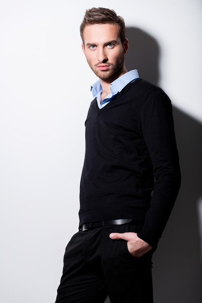 Fashion portrait of young man in black pullover and blue shirt with contrast shadows