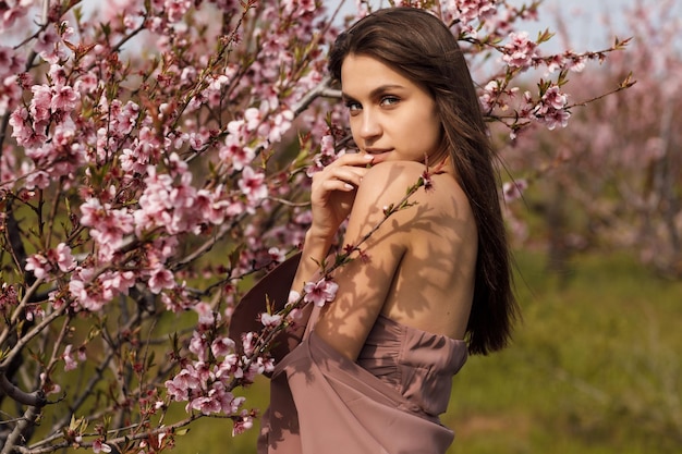 fashion portrait of young woman in dress in blooming garden