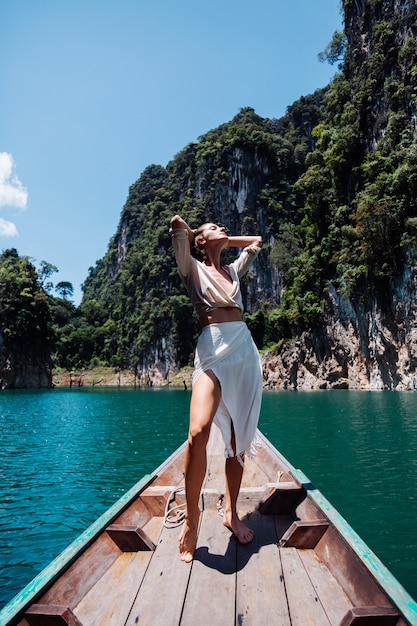 Fashion portrait of young woman on vacation, on asian wooden boat