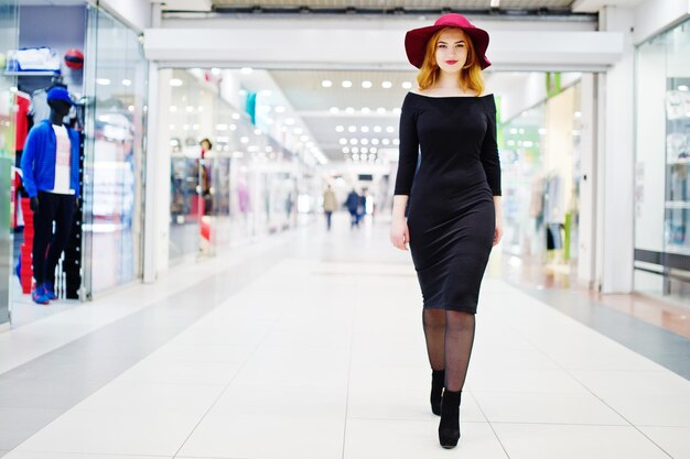 패션 빨간 머리 소녀는 무역 쇼핑 센터에서 포즈를 취한 검은 드레스와 빨간 모자에 착용 사진 톤 스타일 Instagram 필터