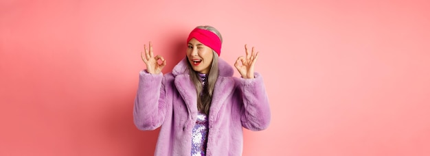 Free photo fashion and shopping concept stylish asian granny saying all okay and winking trendy senior woman in
