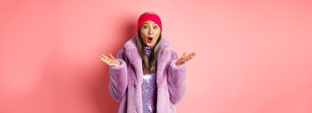 Fashion and shopping concept surprised elderly asian woman in stylish fakefur coat and headband look