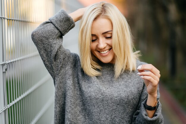 fashion street photo session of stylish young lady in a grey clothes