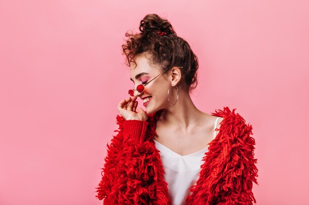 ピンクの背景に笑みを浮かべて赤い服のファッションの女性