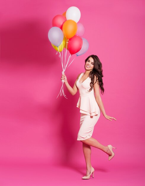 Fashion woman with balloons on pink