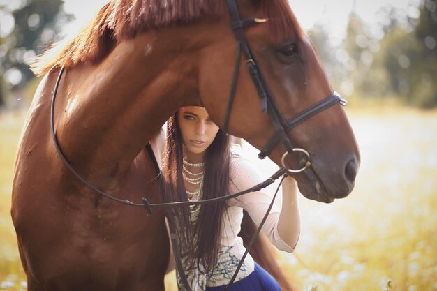 Fashion woman with long brown hair posing with brown horse.