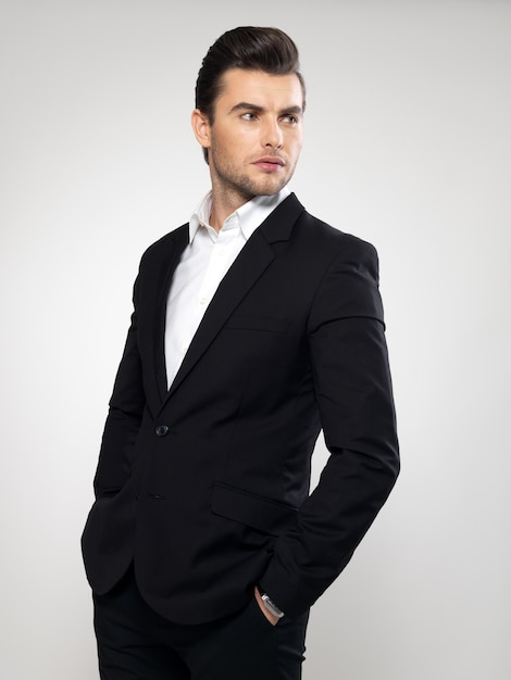 Fashion young businessman black suit casual  poses at studio