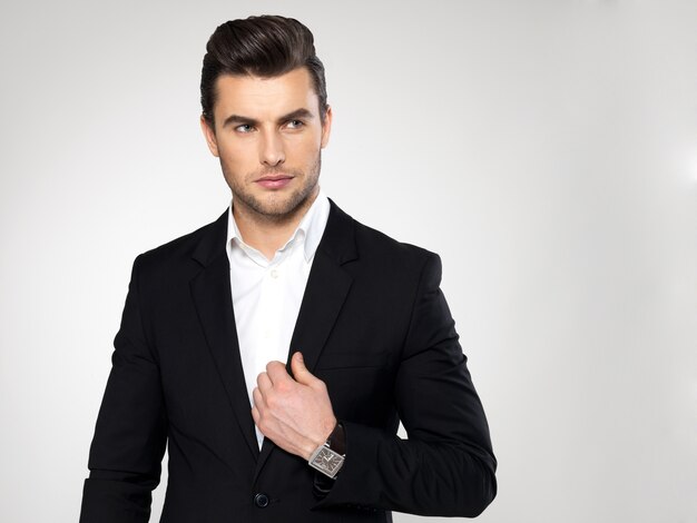 Fashion young businessman black suit casual  poses at studio