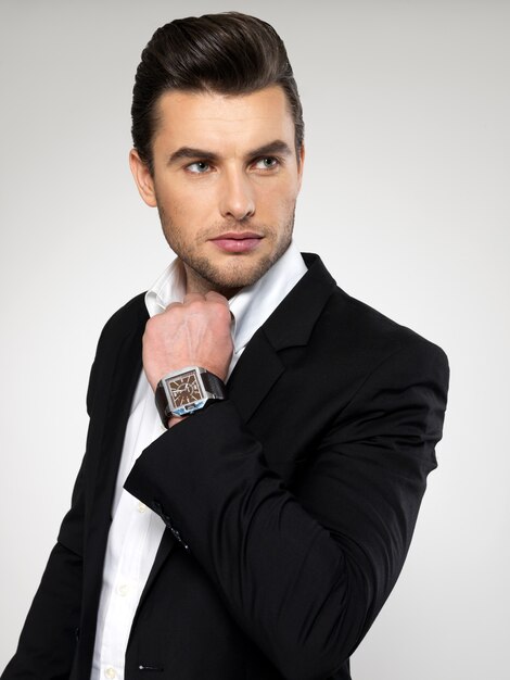 Fashion young businessman black suit casual  poses at studio