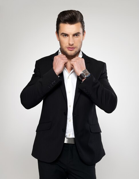 Fashion young businessman black suit casual  poses at studio