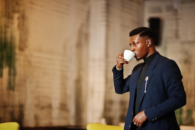 Fashionable african american man in suit standing at cafe with cup of coffee