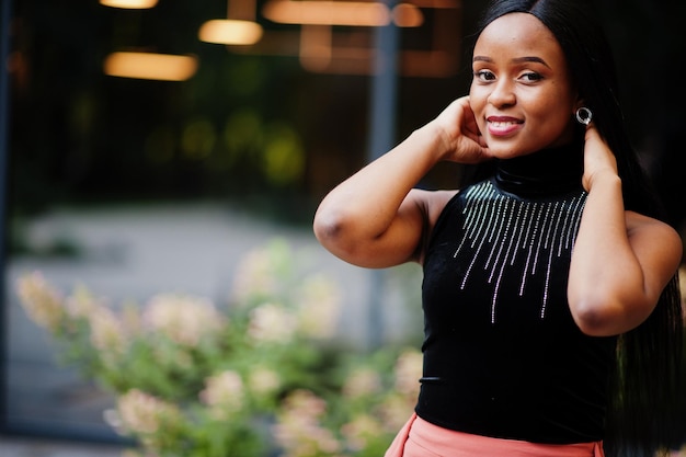 Free photo fashionable african american woman in peach pants and black blouse pose outdoor