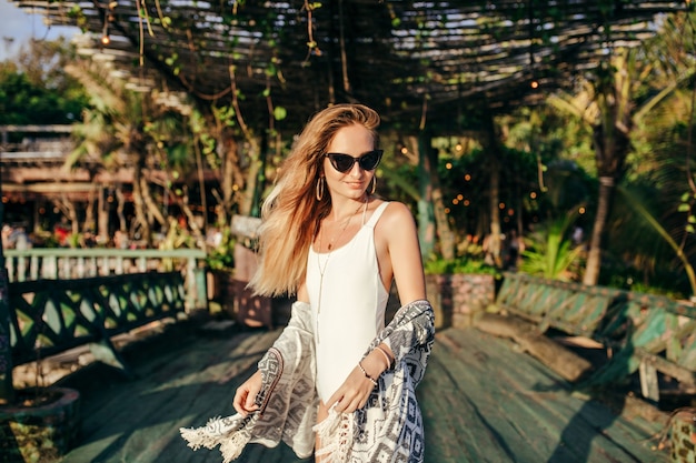 Fashionable blonde woman in white swimwear in exotic place